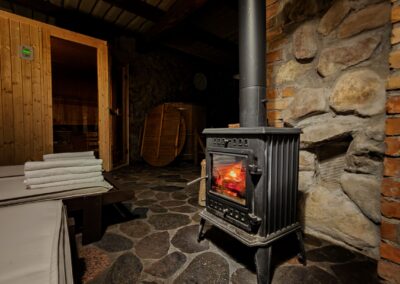 Warm sauna room in Płociczno featuring a classic wood-burning stove and rustic stone walls.