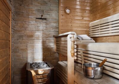 Featuring a relaxing sauna interior with wooden benches and a stone wall heater for a serene escape.