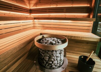 A beautifully designed wooden sauna interior featuring a modern heater with stones, creating a relaxing atmosphere.